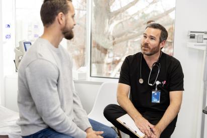 Ein Arzt führt ein Gespräch mit einem Patienten in einer Praxis.
