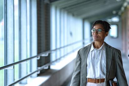 Zwei Personen gehen durch einen Flur, eine trägt ein Namensschild mit 