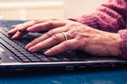 alte Frau arbeitet am Laptop