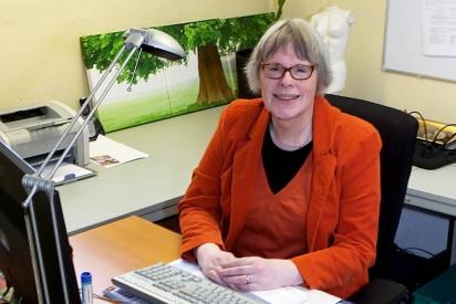 Person im roten Kostüm sitzt am Schreibtisch