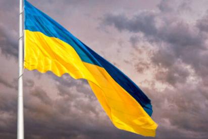 Ukrainische Flagge weht vor Himmel in der Dämmerung mit dramatischer Wolkenformation.
